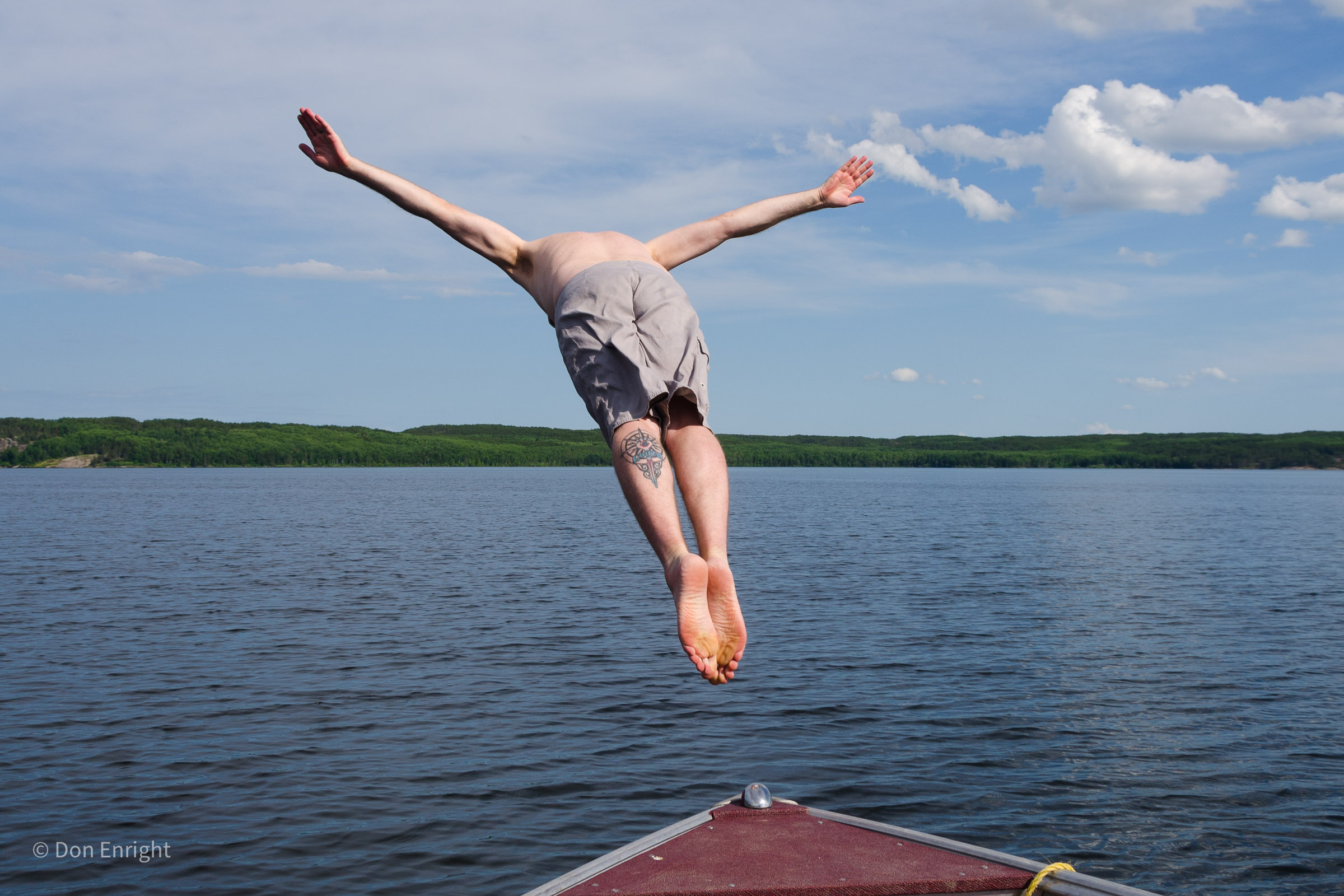 Man joyfully jumping off boat into water